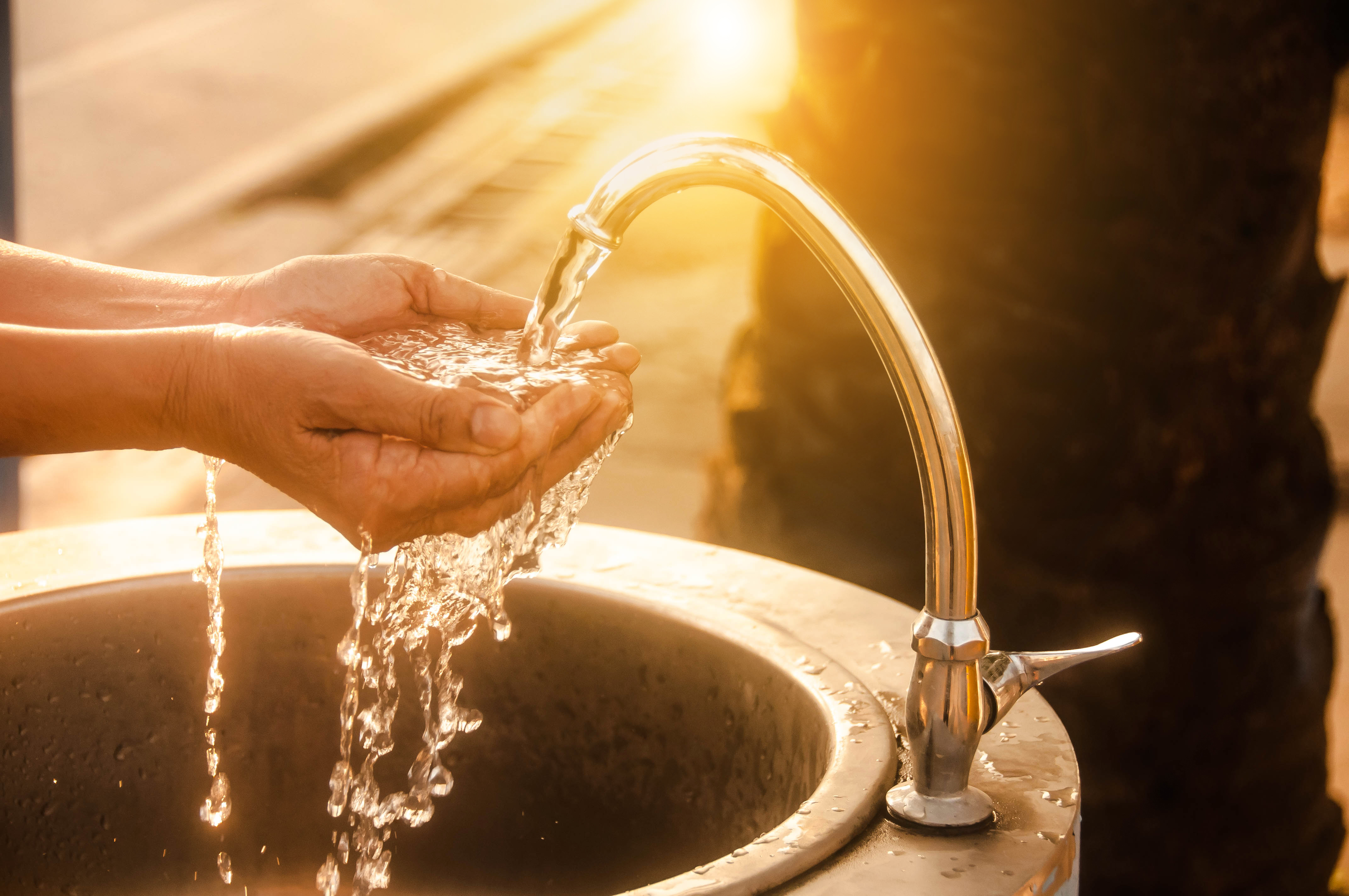 immagine sezione istituzioni - persona che si bagna le mani con l’acqua di un rubinetto
